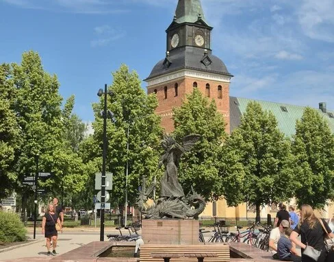 Sankt Mikael-statyn som besegrar draken, med Mora kyrkas torn i bakgrunden. Skulpturen är gjord av Per Nilsson-Öst och restes 1980.