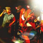 Livekonsert med Angus – The Ultimate AC/DC Tribute på scen, där bandet framför klassiska AC/DC-låtar med sång, elgitarr och kraftfull rockenergi.