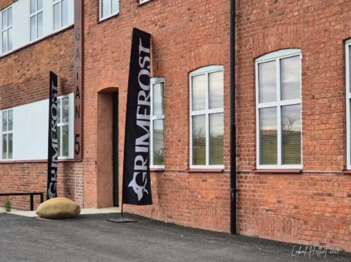 Grimfrost Lagerbutik i Falköping med tegelbyggnad, svarta flaggor och entré på Bangatan 5.